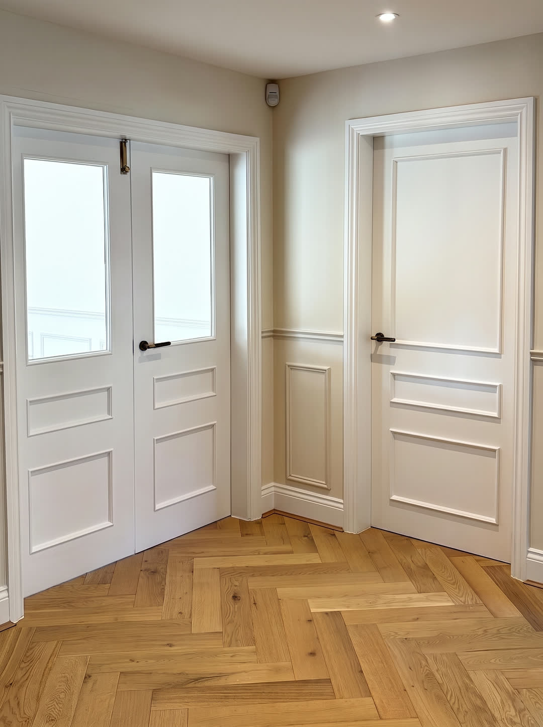 Hall with glazed double doors, a panelled door and herringbone oak floor