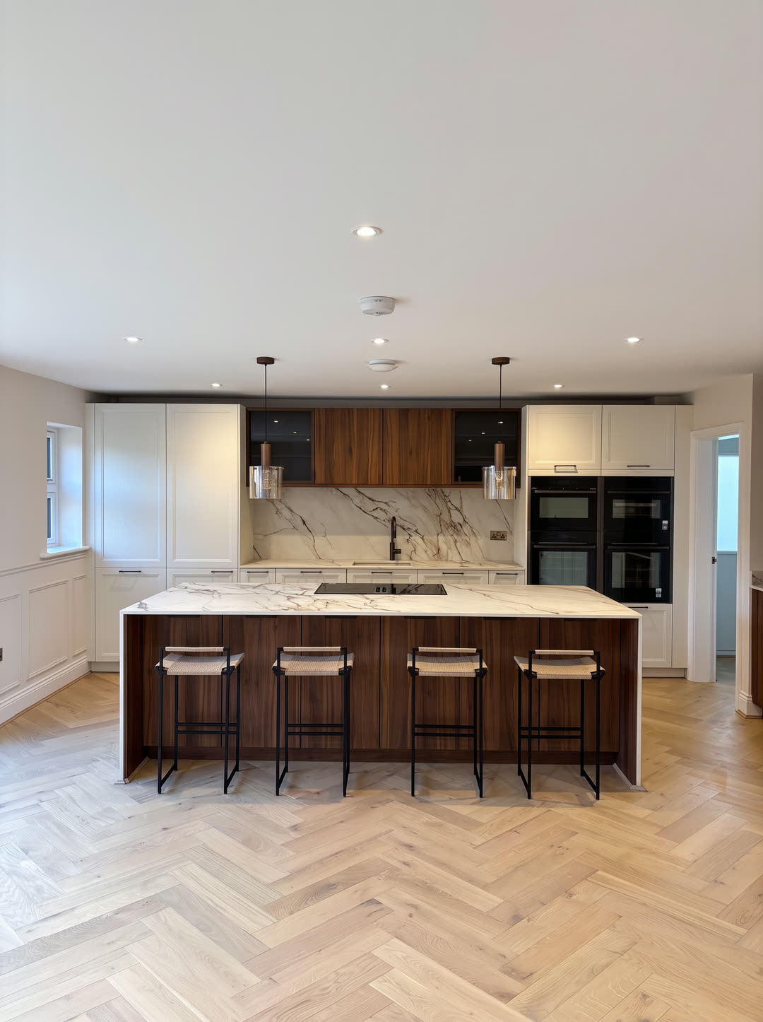 The kitchen straight on: dark oak island, cream shaker units and marble-effect splashback