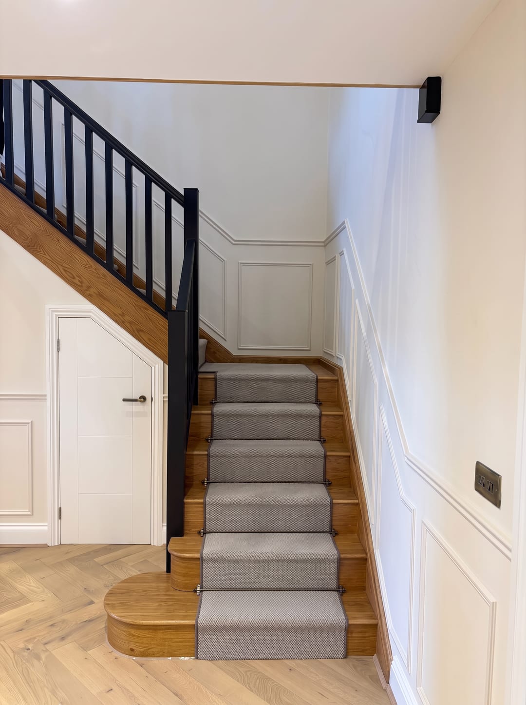 Bespoke oak staircase with a grey runner and panelled walls