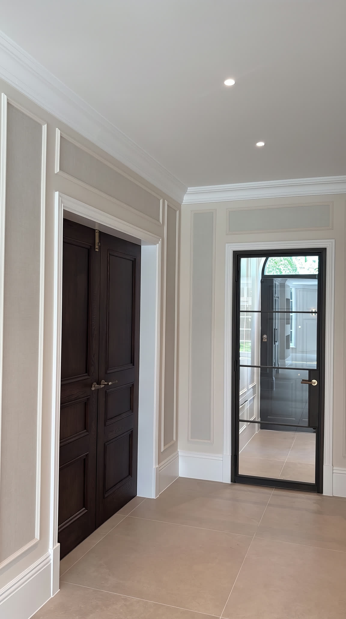 Panelled hall with dark oak double doors and a steel-framed glazed door