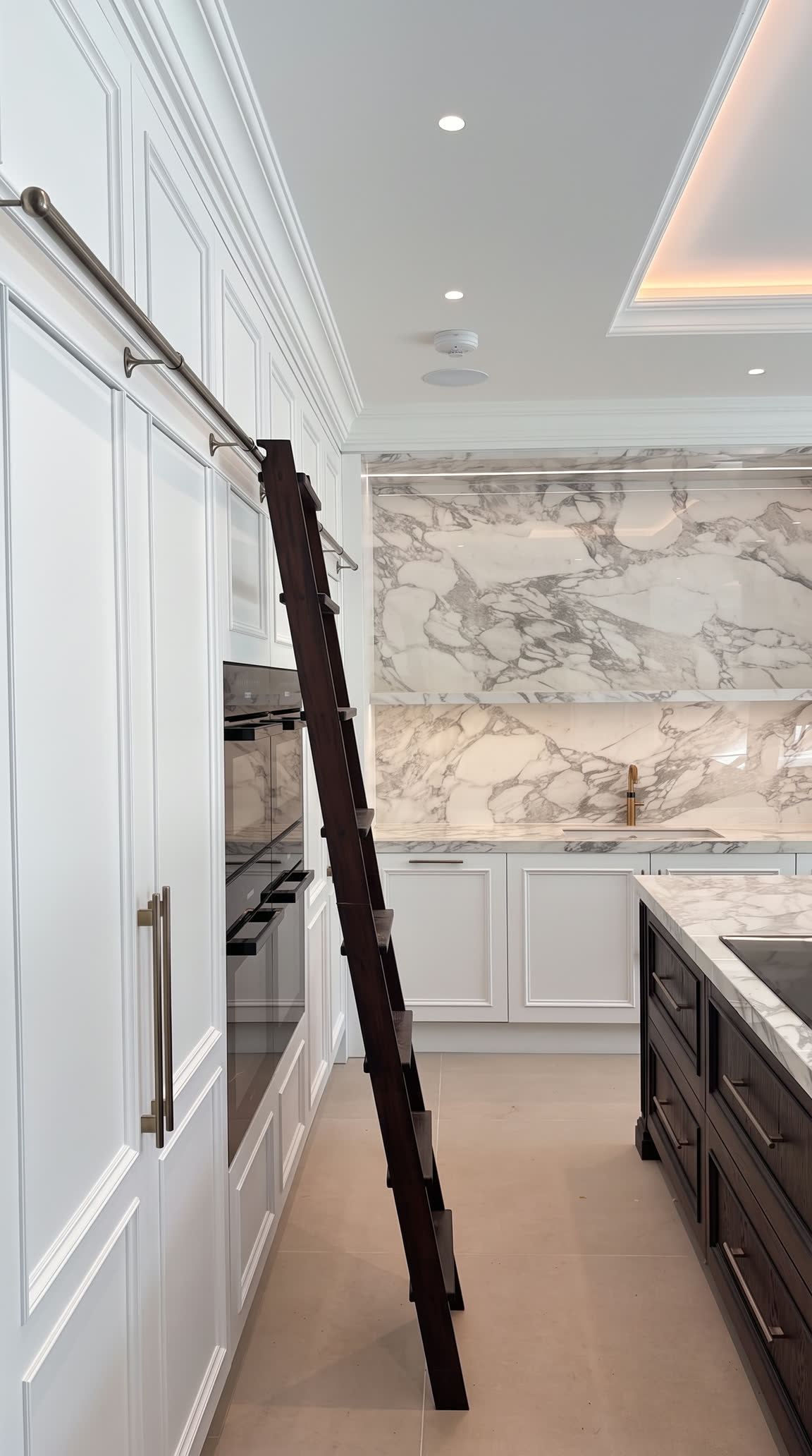 Library ladder along full-height painted cabinetry