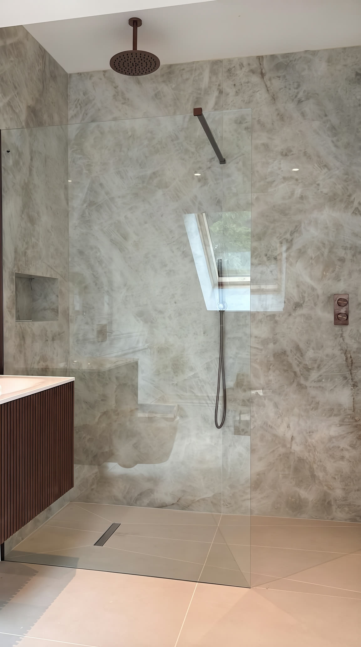 Walk-in shower: frameless glass screen, linear floor drain and grey marble walls