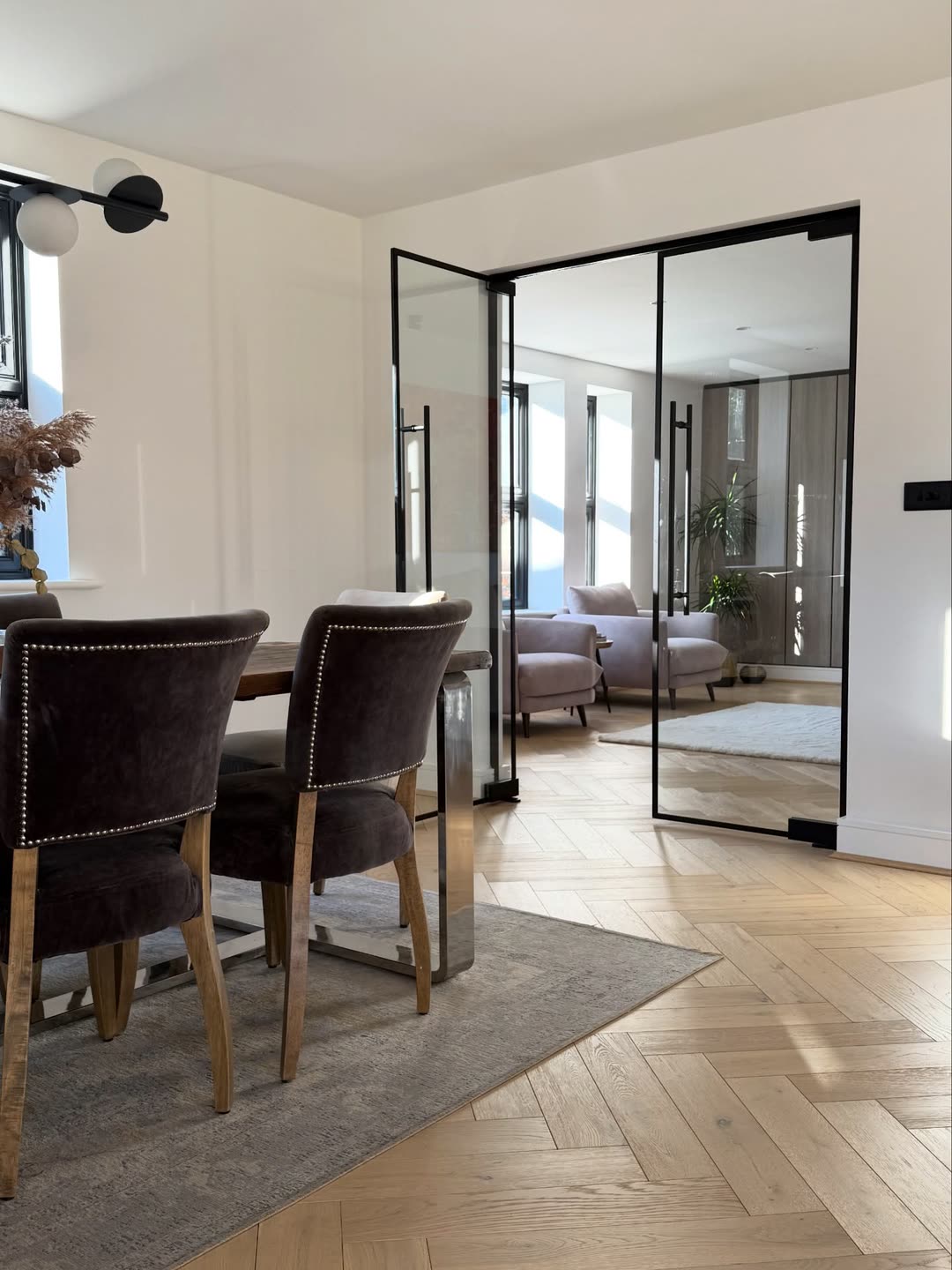 Dining area with upholstered chairs beside glazed doors to the living room