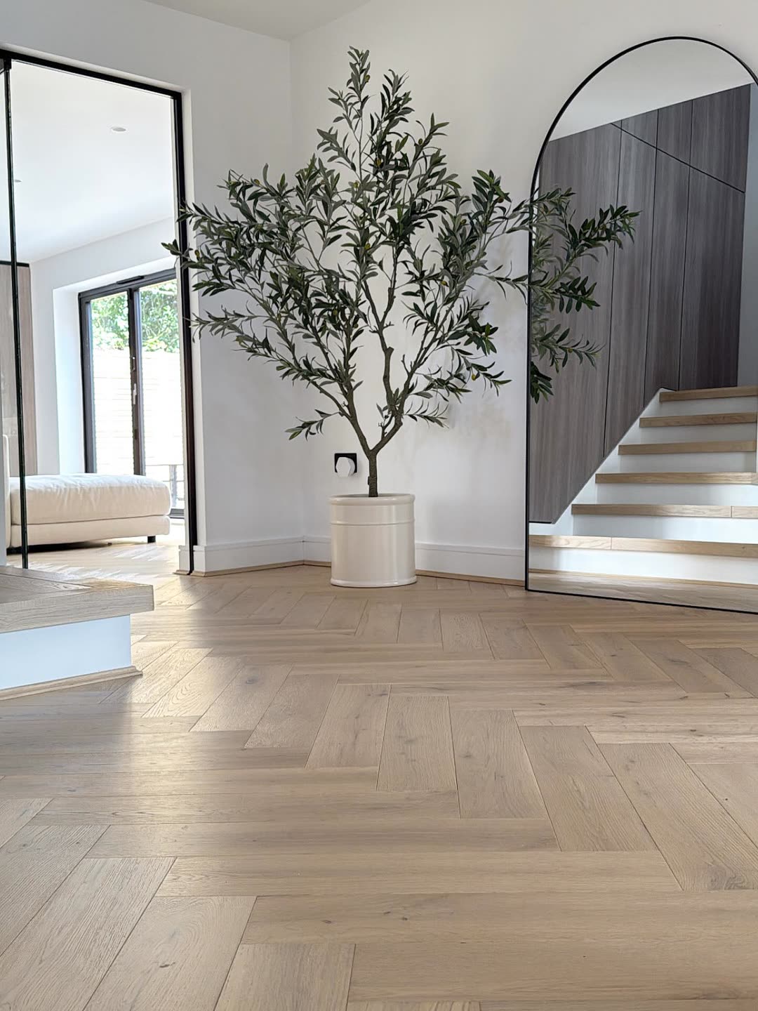 Hall with an olive tree, arched mirror and oak staircase