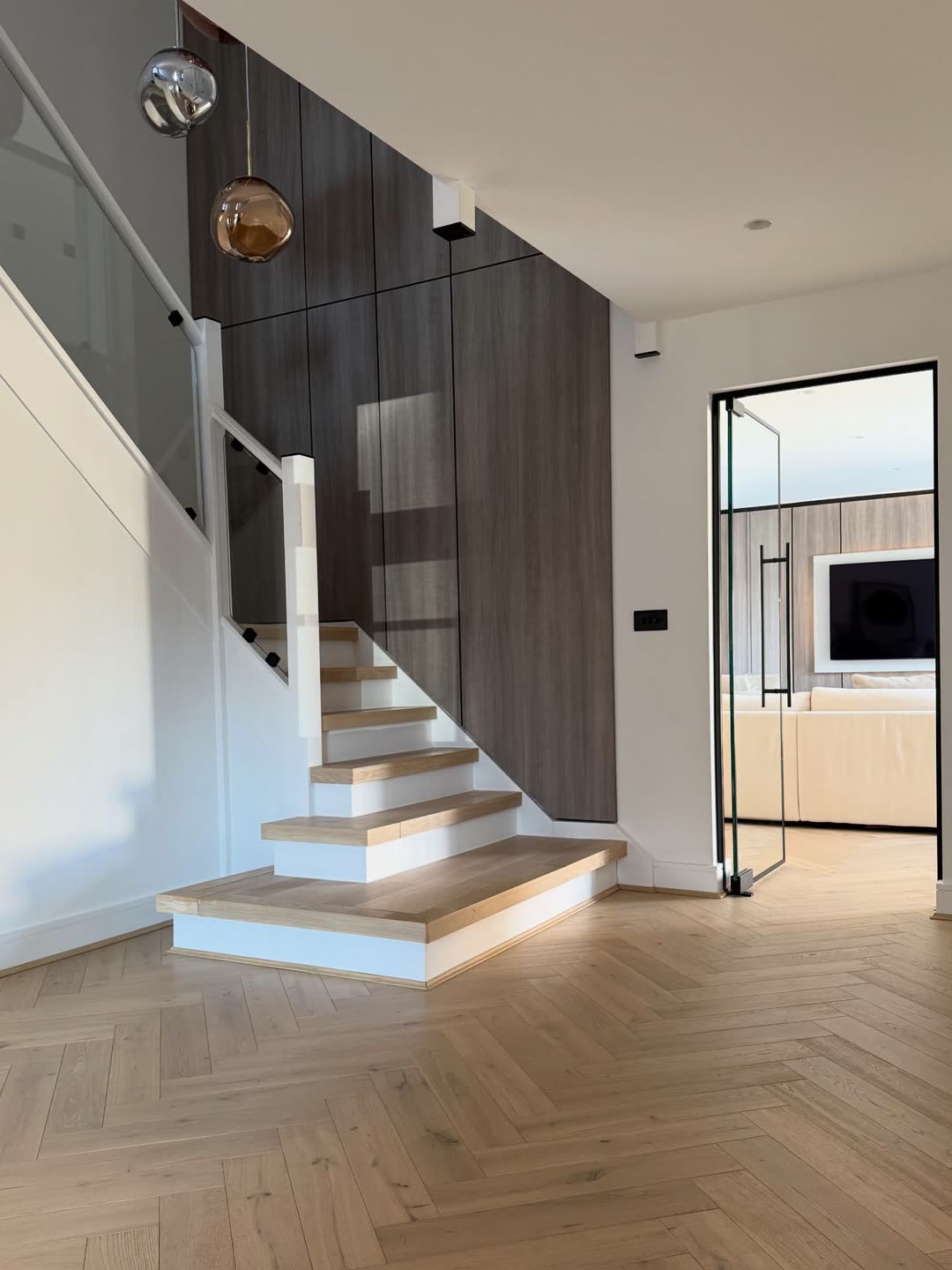 Floating oak stair beneath copper glass pendants